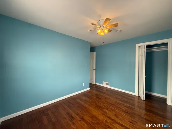 an empty room with wooden floor and a ceiling fan