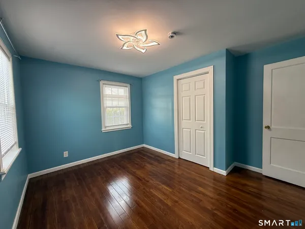 an empty room with wooden floor chandelier and windows