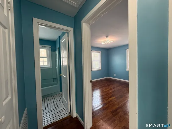a view of a hallway view with wooden floor and a bathroom