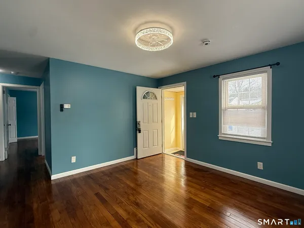a view of an empty room with wooden floor and a window