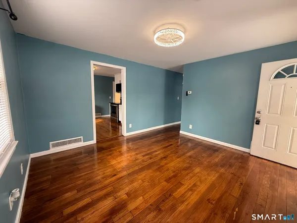 a view of an empty room with wooden floor and a window
