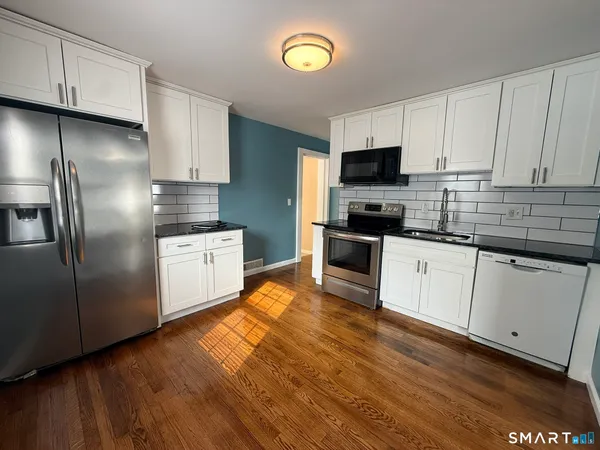 a kitchen with cabinets stainless steel appliances and wooden floor