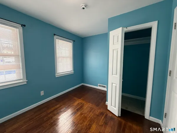 an empty room with wooden floor closet and windows