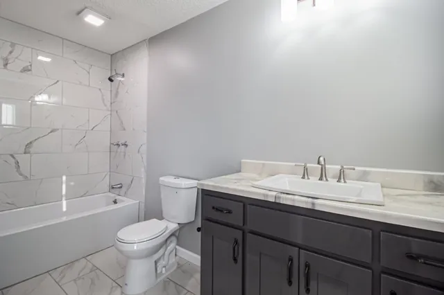 a bathroom with a granite countertop sink a toilet and shower