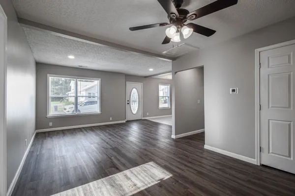 a view of an empty room with window and wooden floor
