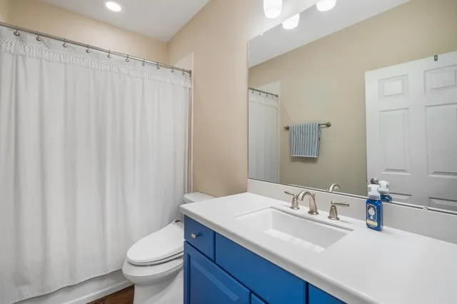 a bathroom with a granite countertop sink toilet and a mirror