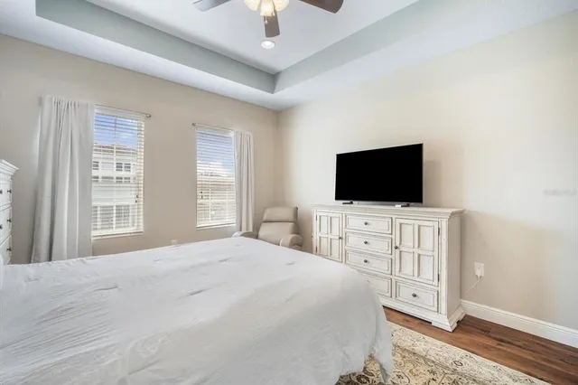 a bedroom with a flat screen tv on dresser and a chandelier