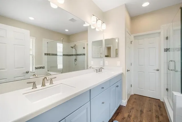 a bathroom with a sink double vanity granite tub shower and a mirror