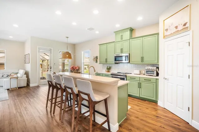 a kitchen with stainless steel appliances granite countertop a table chairs sink and cabinets