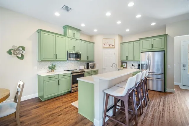 a kitchen with stainless steel appliances a table chairs refrigerator and cabinets