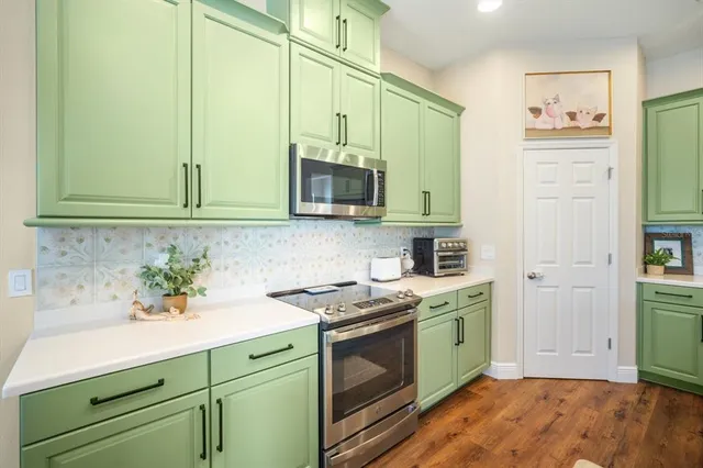 a kitchen with stainless steel appliances white cabinets and a stove top oven