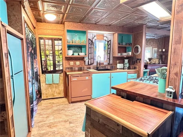 a room with stainless steel appliances kitchen island granite countertop a refrigerator a sink a stove top oven and a dining table with wooden floor