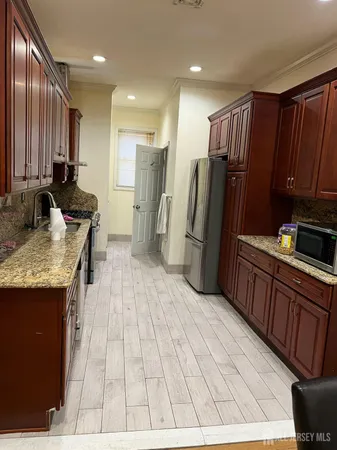 a kitchen with stainless steel appliances granite countertop a refrigerator a sink a stove a microwave and wooden cabinets