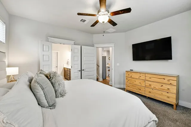 a bedroom with a bed a flat screen tv and a chandelier