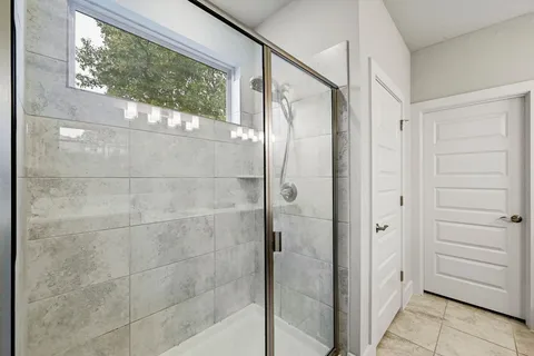 a bathroom with a glass shower door and a window