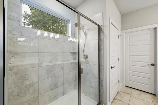 a bathroom with a glass shower door and a window