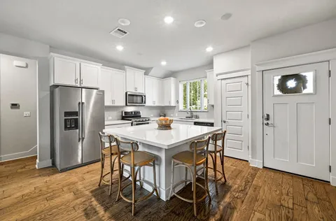 a kitchen with stainless steel appliances a refrigerator a stove a sink dishwasher and a refrigerator with wooden floor