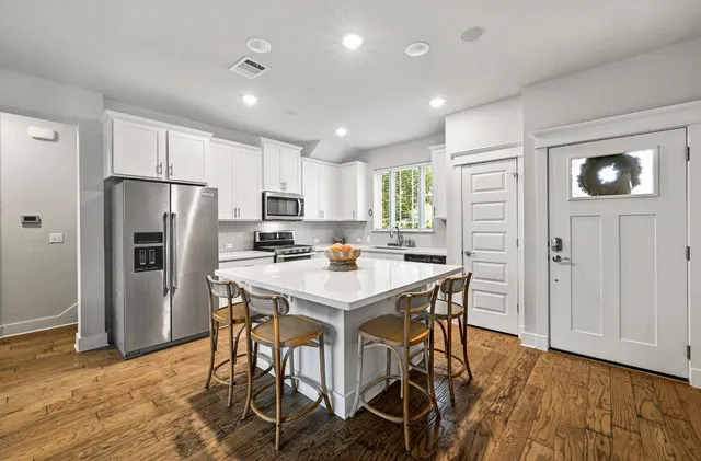 a kitchen with stainless steel appliances a refrigerator a stove a sink dishwasher and a refrigerator with wooden floor