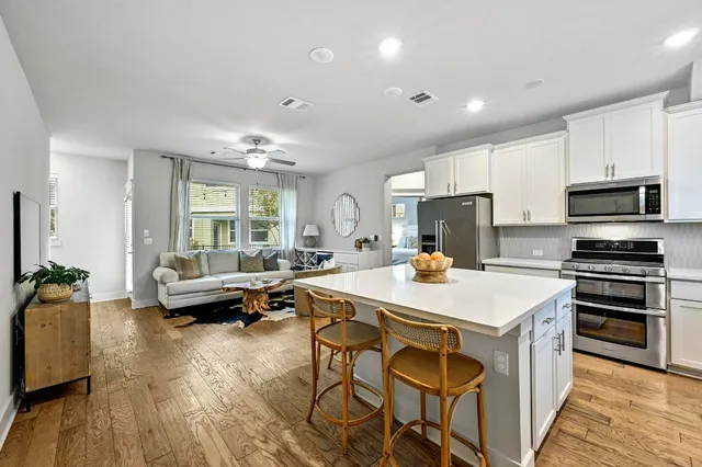 a kitchen with a stove a refrigerator and a dining table with wooden floor