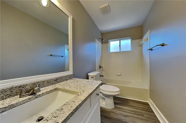 a bathroom with a granite countertop sink a toilet and shower