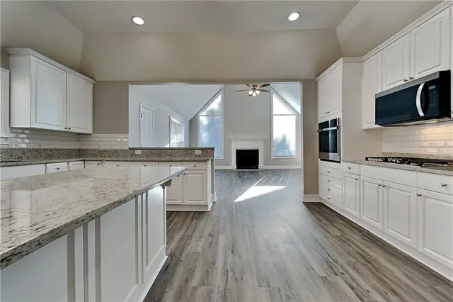 a large kitchen with stainless steel appliances granite countertop a lot of counter space and wooden floor