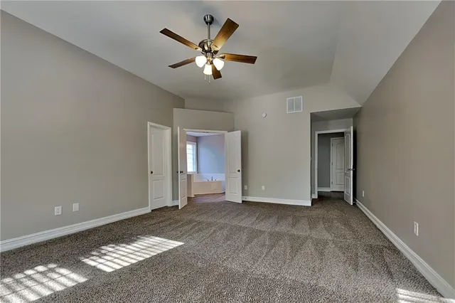 a view of an empty room with chandelier fan and fire place