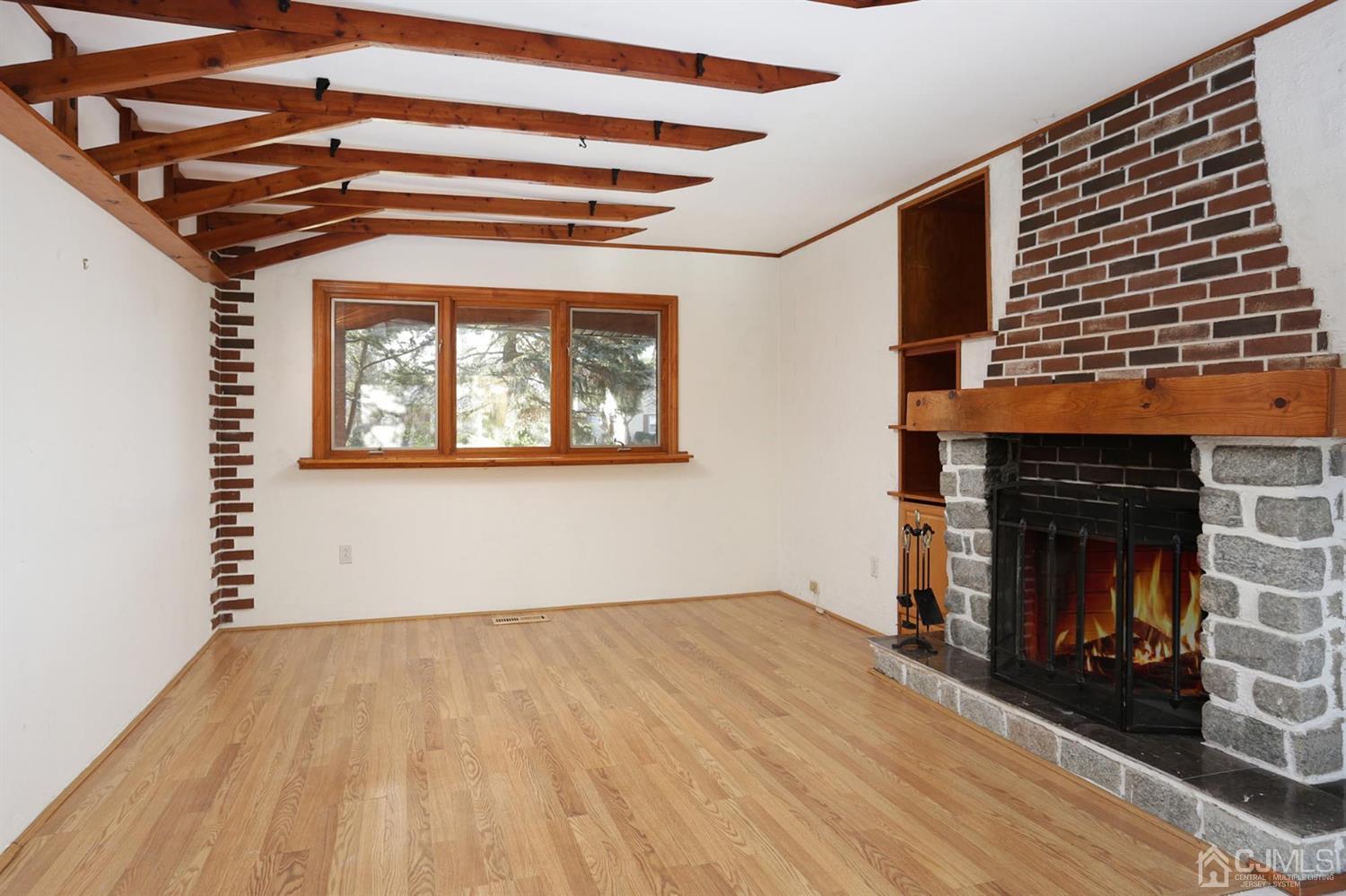 75 Lakeridge Drive Old Bridge, NJ 07747 - Photo 14 of 26 an empty room with wooden floor a fireplace and windows