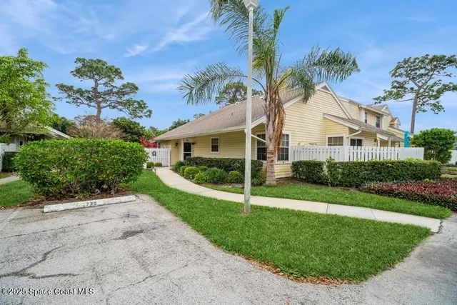 a view of a white house with a yard and potted plants
