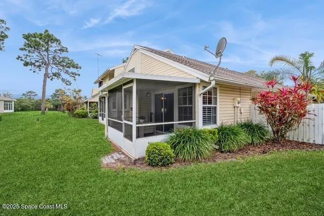 a white house with a small yard and large trees