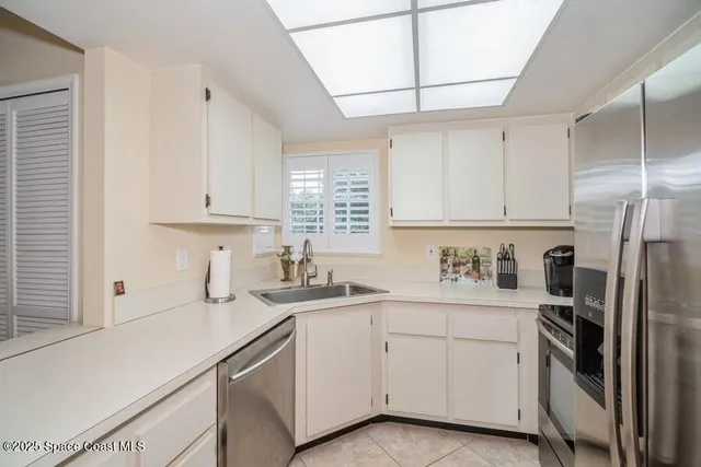 a kitchen with a sink dishwasher a refrigerator and white cabinets