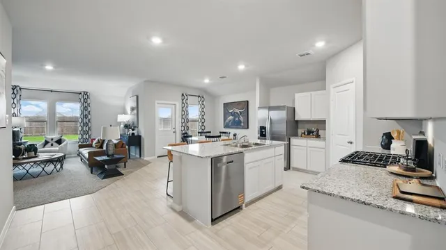 a kitchen with stainless steel appliances granite countertop white cabinets and a stove a sink