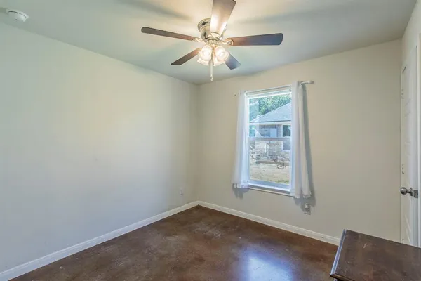 an empty room with windows and fan