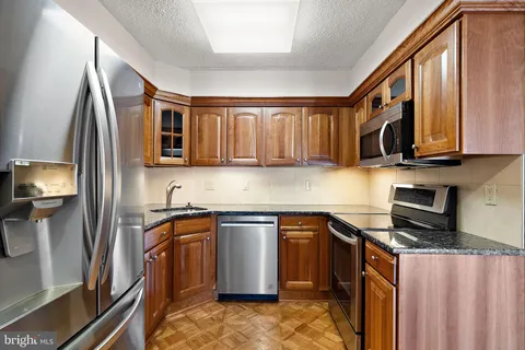 a kitchen with stainless steel appliances granite countertop a sink stove microwave and refrigerator