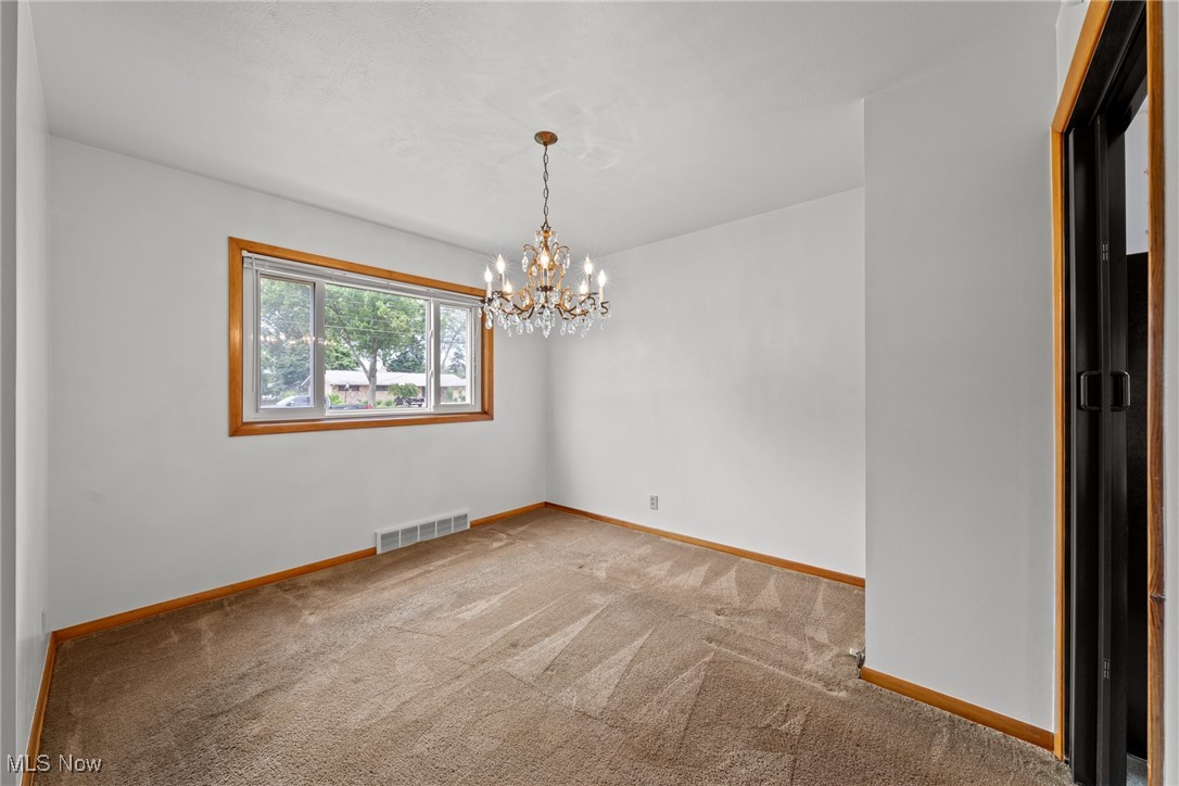 29776 Arthur Road Wickliffe, OH 44092 - Photo 9 of 49 Carpeted spare room featuring a chandelier and baseboards