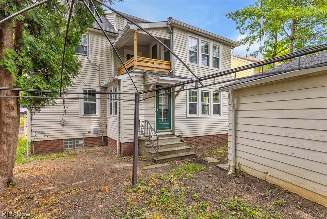 2972 Yorkshire Road Cleveland Heights, OH 44118 - Photo 37 of 44 Rear exterior featuring light-colored siding, a second-story balcony with natural wood railing, a green entry door with sidelights, and a detached structure with matching siding