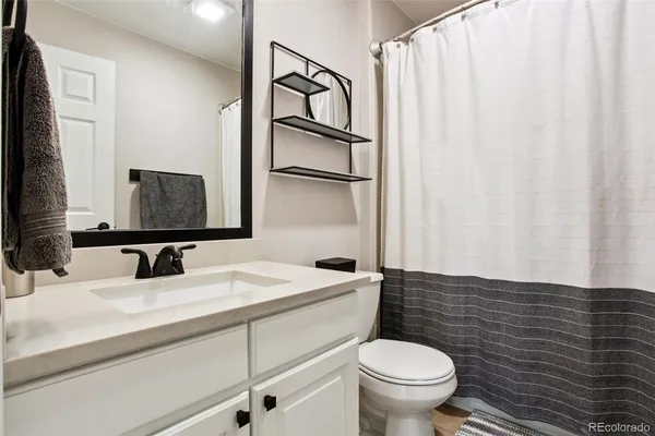 a bathroom with a granite countertop sink toilet and mirror
