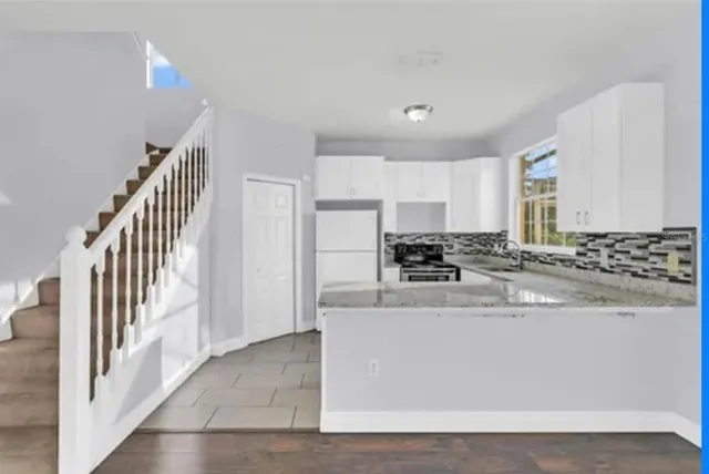 a view of a kitchen with stainless steel appliances granite countertop a stove a sink and a refrigerator