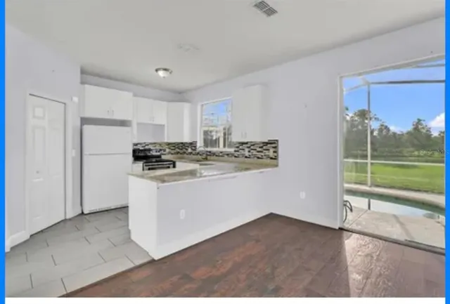 a kitchen with a refrigerator a stove and white cabinets with wooden floor