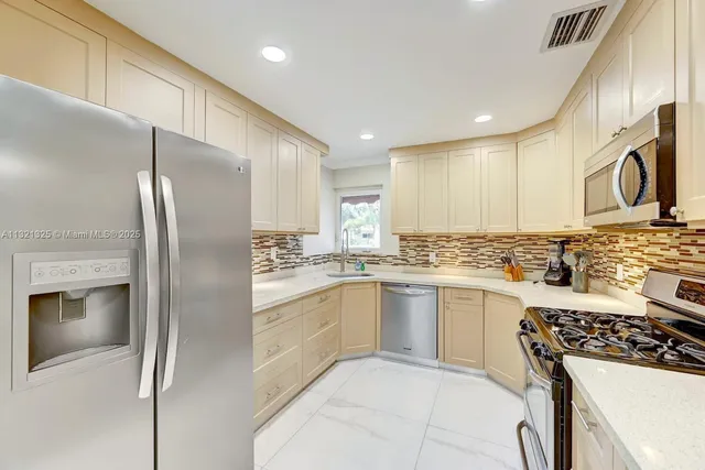 a kitchen with stainless steel appliances granite countertop a stove a sink and a refrigerator