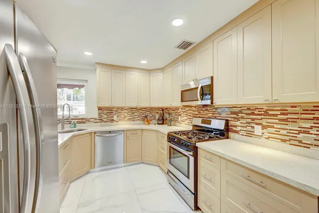 a kitchen with stainless steel appliances granite countertop a stove a sink and a refrigerator