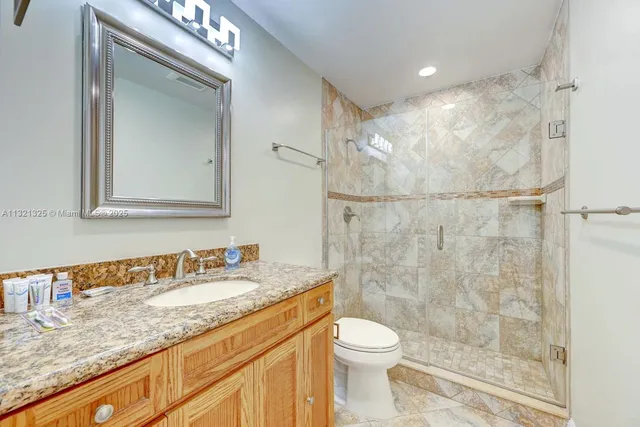 a bathroom with a granite countertop sink a toilet and shower