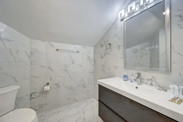 a bathroom with a sink toilet a mirror and shower