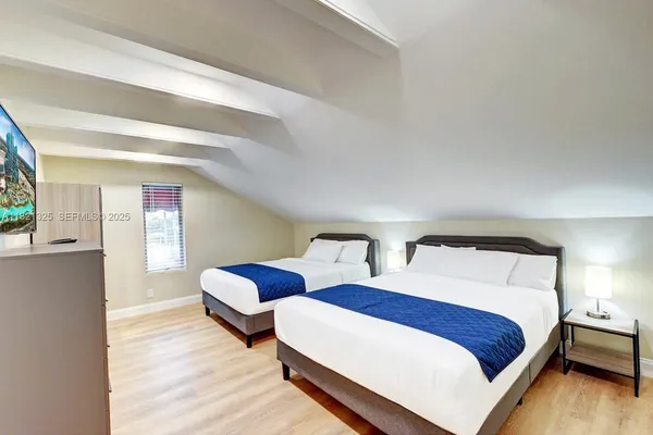 a bedroom with two beds and wooden floor