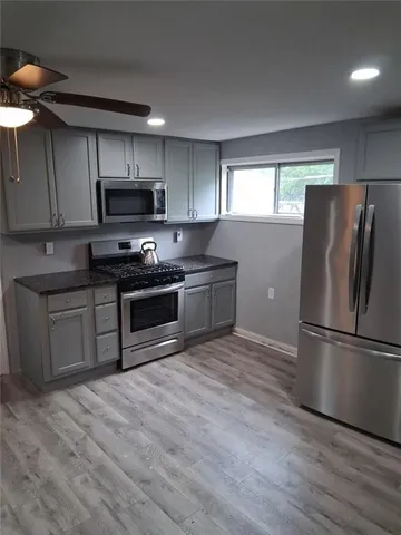 a kitchen with stainless steel appliances a refrigerator a sink a stove a microwave and wooden floors