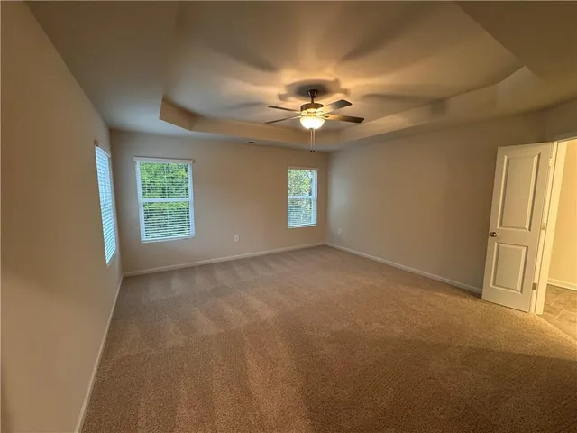 an empty room with windows and chandelier fan
