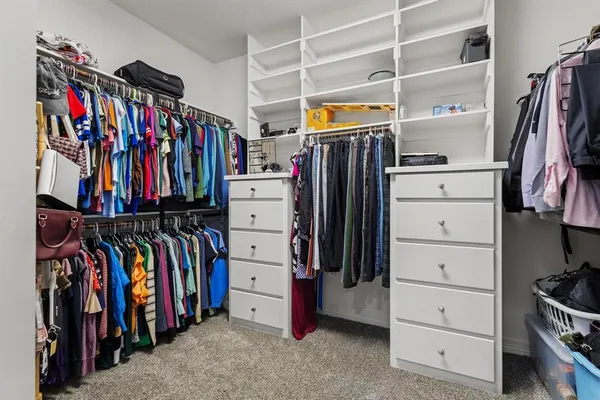 a view of walk in closet with clothes and shoes