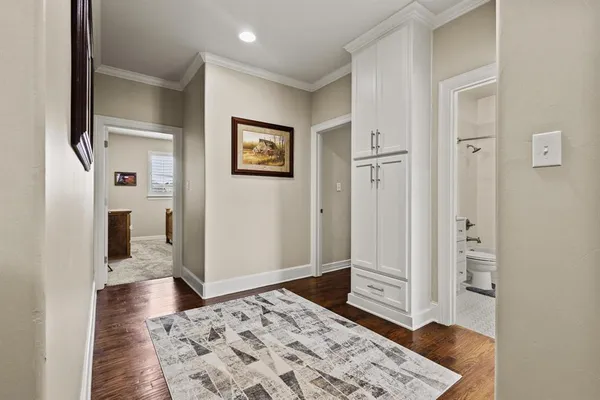 a view of a hallway with bathroom and wooden floor