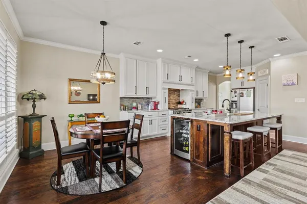 a kitchen with stainless steel appliances a dining table chairs stove and cabinets