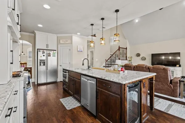 a room with stainless steel appliances kitchen island granite countertop a table chairs and a refrigerator