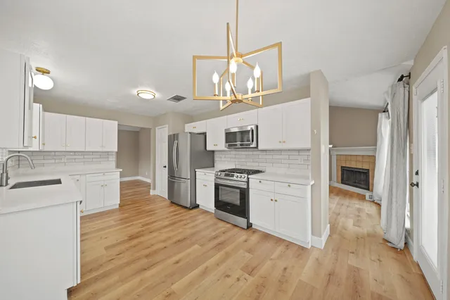 a large kitchen with cabinets wooden floor and stainless steel appliances